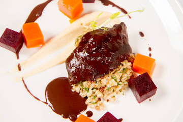 Sticker - Beef cheeks with vegetables, roasted parsley root mousse , pearl barley, dark chocolate and demi glace sauce on a white background