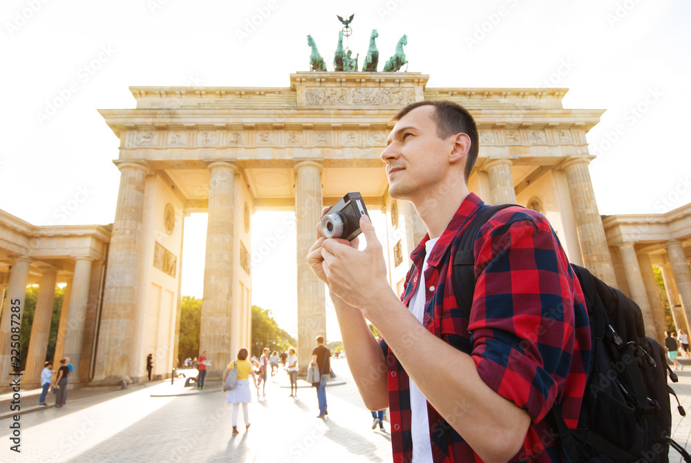 Travel in Berlin, tourist man with camera in front of Brandenburg Gate, Berlin, Germany - obrazy, fototapety, plakaty 