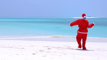 Wall Mural - Man in Santa Claus Hat dancing on sandy beach