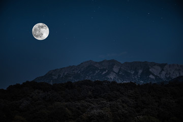 Wall Mural - Mountain Road through the forest on a full moon night. Scenic night landscape of dark blue sky with moon. Azerbaijan
