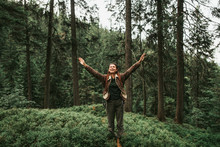 I Am Happy And Free. Full Length Portrait Of Spirited Young Lady With Closed Eyes Enjoying Travel In The Woods. She Is Spreading Arms With Joy And Smiling