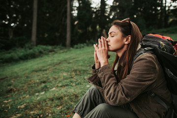 Wall Mural - Healing power of nature. Side view portrait of beautiful girl with closed eyes resting in the forest. She is keeping hands near face and thinking about something important