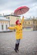 © Михаил Решетников - A red-haired woman in a yellow coat and a red beret is jumping with a red umbrella. A smiling beautiful woman in striped pants and a warm jacket flies with an umbrella, like Merry Poppins.