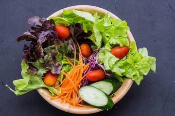 Close up bowl fresh vegetable salad on black back ground. Clean eating, dieting, vegan food concept.