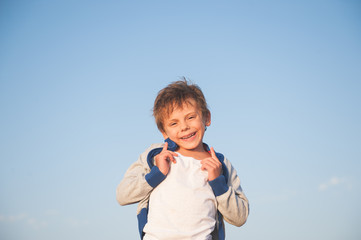 happy delightful laughing little child in sweater on blue sky background