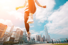 Woman Runner Jumping Over The Camera  With Hong Kong Cityscape In Background