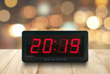 Red Led Light Illuminated Numbers 2019 On Digital Electric Alarm Clock Face On Brown Wooden Table Top With Defocused Colorful Christmas Lights Bokeh Background, Time Symbol For Beginning New Year