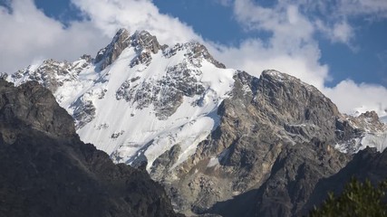 Wall Mural - Fantasy-like awesome mountain beauty. Melting clouds. Clouds roiling and flowing over peaks. Bezengi, Kabardino-Balkar Republic, Caucasus, Russia. Summer day timelapse video