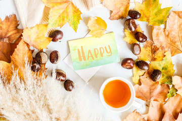 Autumn maple leaves, cup of black tea and card with word Happy isolated on a gray background. Top view. Flat lay.