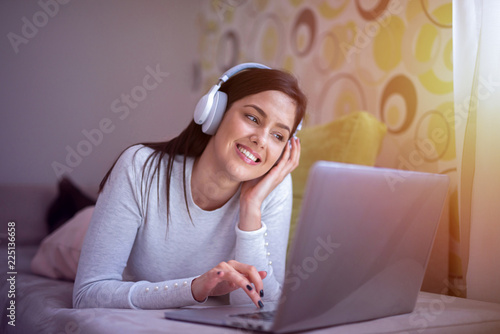 Fotografía Sweet young girl lying on her bed with headphones on her head