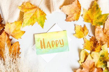 Autumn maple leaves and card with word Happy isolated on a gray background. Top view. Flat lay.