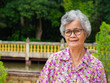 © meeboonstudio - Portrait of senior asian woman stand wearing glasses and smiling in garden.