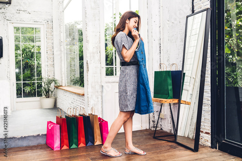 Foto  Happy woman shopping and choosing clothes looking to mirror in a store