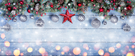 Wall Mural - christmas baubles with star in fir branches on snowy wooden plank