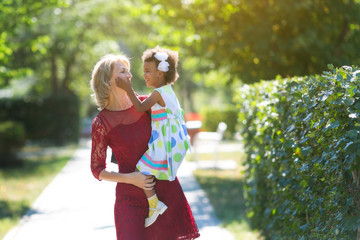 A white woman with a black daughter in her arms. A woman holding a foster-child in her arms created a happy family.