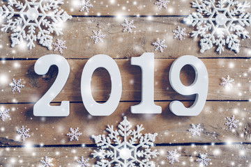 Wooden numbers forming the number 2019, For the new year and white snow with snowflakes on rustic wooden background.