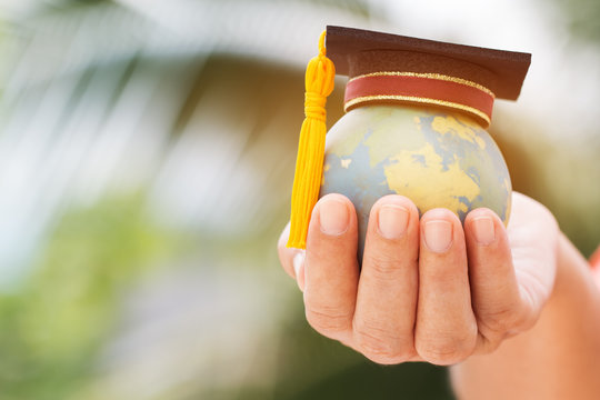 Graduate or Education knowledge learning study international abroad concept : Graduation cap on opening textbook with blur earth world globe model map in outdoor of campus, Back to School