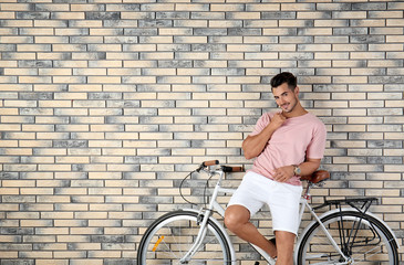 Sticker - Handsome young hipster man with bicycle on brick wall background