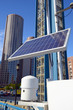 Solar panel in urban environment with buildings and skyscrapers in background with blue sky