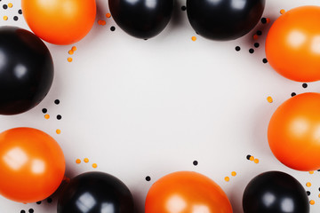 Black and orange balloons and confetti frame for Halloween card or invitation. Flat lay.