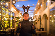 People, holidays and christmas concept - surprised man in deer's horns holding two bengals light or sparklers outdoors
