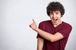 © sementsova321 - Positive curly guy keeps mouth opened, exclaims with happiness, points aside at blank copy space for your advertising content, wears casual t shirt, Hey, look on left, please. Advertisement concept