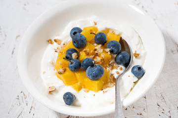 Wall Mural - thick Greek yogurt with mango and blueberries, closeup