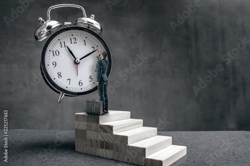 Fotografía Businessman stands on stairs and tries to change clock hand position