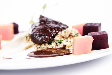 Sticker - Beef cheeks with vegetables, roasted parsley root mousse , pearl barley, dark chocolate and demi glace sauce on a white background