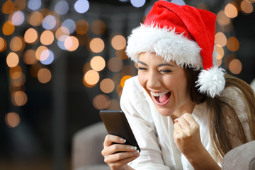 Wall Mural - Excited woman reading text on a phone on christmas