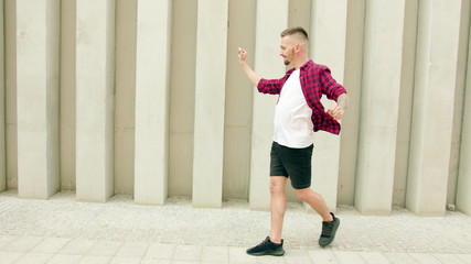 A young man dressed in dancing in the street. Long shot. Dolly shot