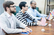 © Seventyfour - Serious confident consuls of different countries attentively listening to speaker and sitting in row at table at international meeting