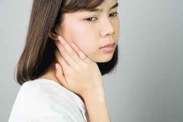 Wall Mural - Asian girl in white casual dress catch that shoulder, Because of the pain of hard work. Or something hit the shoulder. on a gray background gives a soft light.