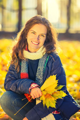 Young beautiful woman enjoys sunny autumn day in the park