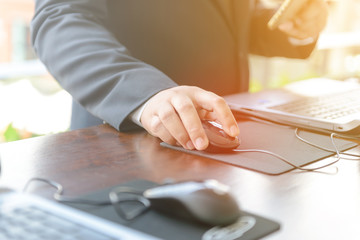 hand of businessman touching a computer mouse with laptop computer