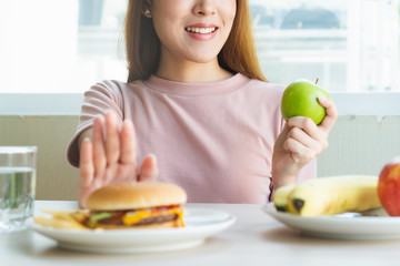 Wall Mural - Woman on dieting for good health concept. Woman doing cross arms sign to refuse junk food or fast food (hamburger and potato fried) that have many fat.