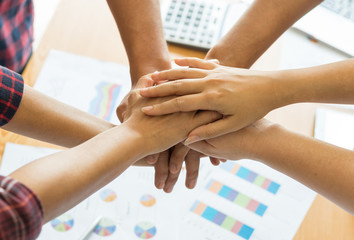 Wall Mural - close up hand of business partnership people stacking hands finishing up meeting showing unity over office desk  , business teamwork concept