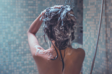 Woman in shower and wash hair she relaxed Image from the back she relaxed .Image from the back