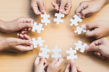 Wall Mural - Hands of diverse people assembling jigsaw puzzle, Youth team put pieces together searching for right match, help support in teamwork to find common solution concept, top close up view