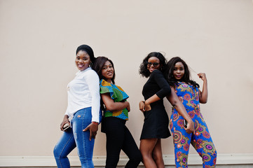 Group of four african american girls posed outdoor against wall.