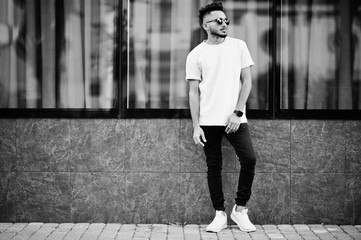 Stylish indian beard man at pink t-shirt, sunglasses. India model posed outdoor at streets of city.