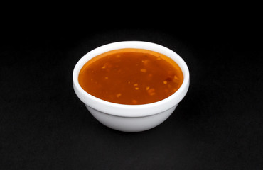 Wall Mural - Sweet and sour sauce in bowl isolated on black background