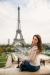 © Aleksandr - Beautiful lady sist on border against of eiffel tower. Lady smile and have fun