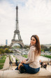 © Aleksandr - Beautiful lady sist on border against of eiffel tower. Lady smile and have fun