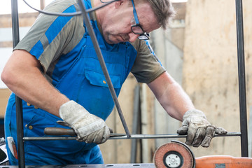 Wall Mural - Worker in factory deburring workpieces of metal, half-body shot