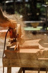 The carpenter works with the electric polisher on the wood.