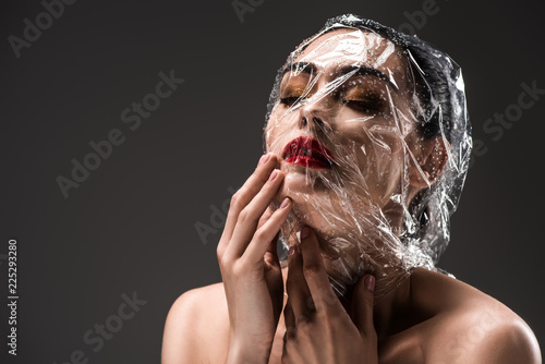 Fotografie, Obraz sensual woman with face wrapped in transparent cellophane with drops isolated on