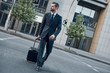 © Friends Stock - Young businessman with a suitcase on wheels walks on the empty road