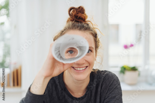 Fotografía junge frau schaut durch ein fernrohr aus papier und lacht