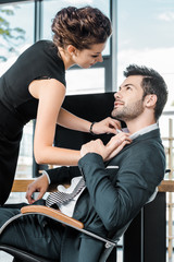 Wall Mural - side view of young businesswoman unbuttoning colleagues shirt at workplace in office